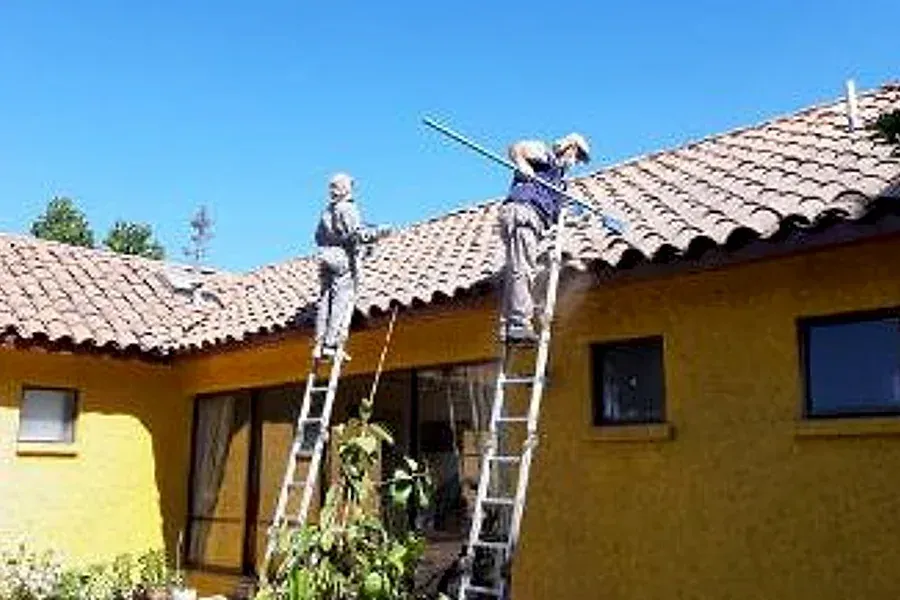 Trabajadores de Techos León en el techo de teja de una casa en Lo Barnechea