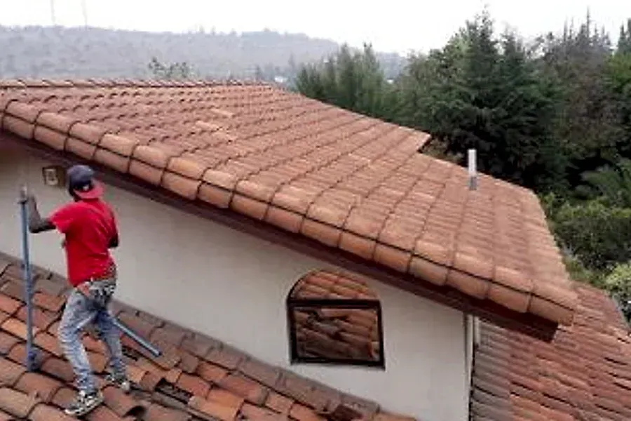 Trabajador sobre un techo de teja colonial en Chicureo
