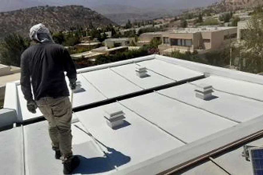 Trabajador sobre un techo de zinc con paneles solares en Lo Barnechea